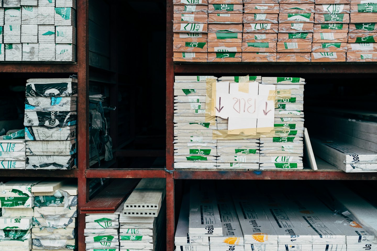 Bouwmaterialen opgeslagen op industriƫle metalen magazijnstellingen.